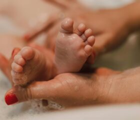 A close-up of a baby's feet during bath time, while his mom checks his Babinski reflex.