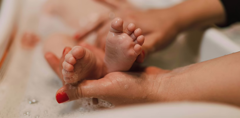A close-up of a baby's feet during bath time, while his mom checks his Babinski reflex.