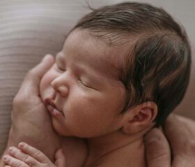 Adult holding her baby with her palm, trying not to touch the soft spot on her head.