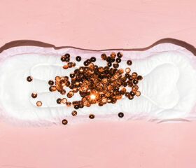 Brown sequins scattered on a pad representing brown discharge during pregnancy.