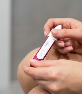 Woman on her period holding a pregnancy test and waiting for the result.