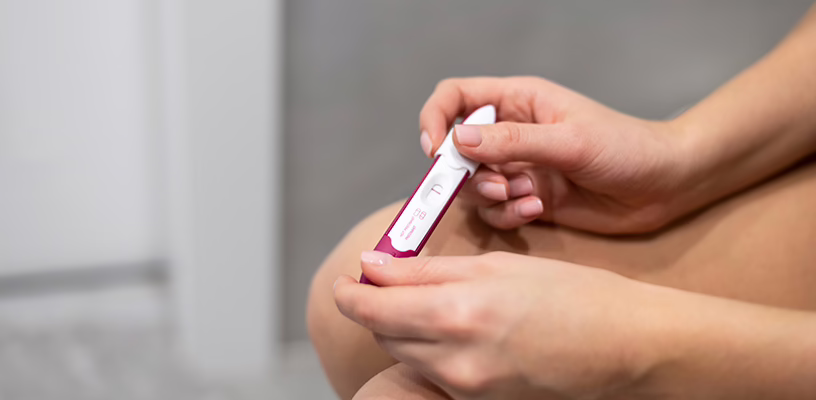 Woman on her period holding a pregnancy test and waiting for the result.