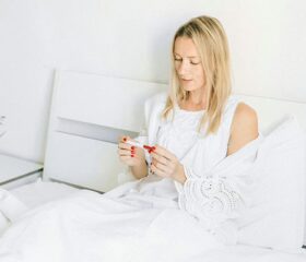 Woman sitting down and viewing a faint line on her pregnancy test.