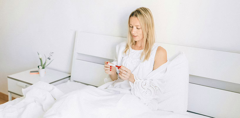 Woman sitting down and viewing a faint line on her pregnancy test.