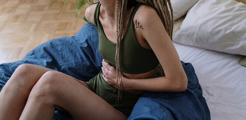 Woman holding her stomach and wondering if her cramps are a symptom of pregnancy.