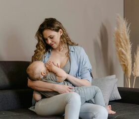 A mom breastfeeding her baby, trying to fully empty her breast to prevent milk blebs.