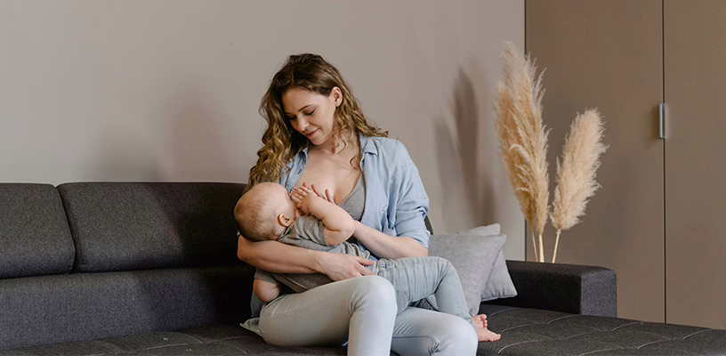 A mom breastfeeding her baby, trying to fully empty her breast to prevent milk blebs.