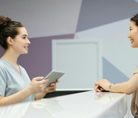 A woman speaking with a receptionist to register for her preconception appointment.