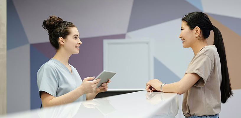 A woman speaking with a receptionist to register for her preconception appointment.