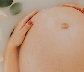 Close-up of a pregnant woman's baby bump, with her belly button protruding.