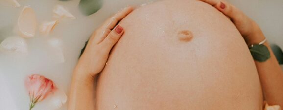 Close-up of a pregnant woman's baby bump, with her belly button protruding.