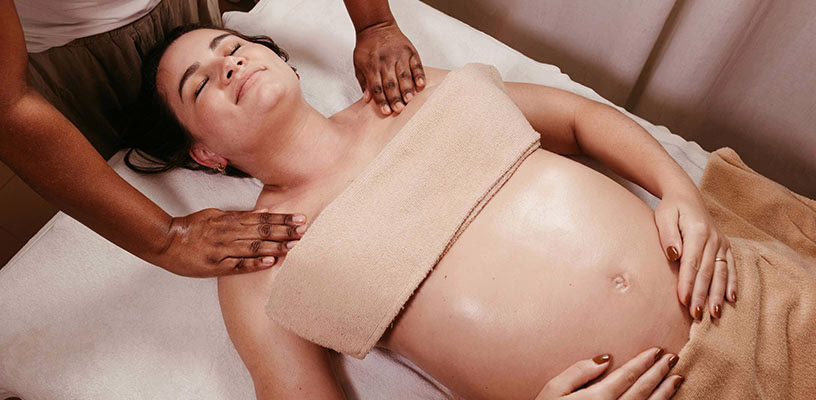 Pregnant woman lying on her back and receiving a prenatal massage.