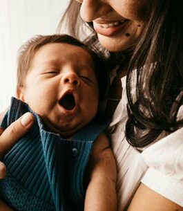 Mom holding her newborn whose mouth is wide open due to the rooting reflex.