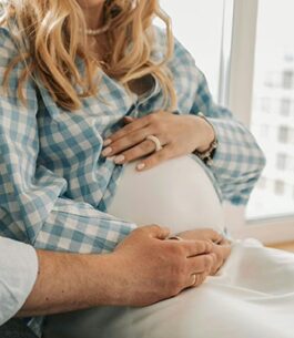 A pregnant woman sitting by her husband with her hands on her baby bump looking for signs of labor.