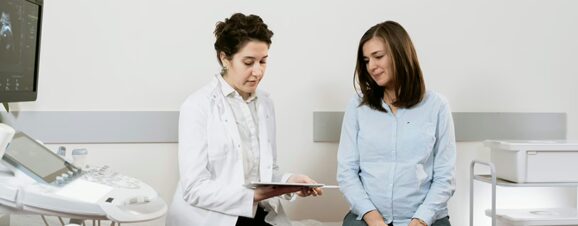 Woman sitting next to her doctor learning that she has a cryptic pregnancy.
