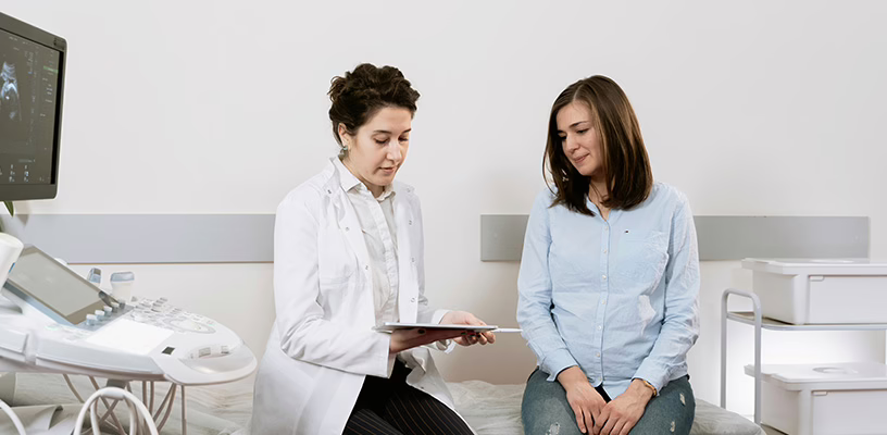Woman sitting next to her doctor learning that she has a cryptic pregnancy.