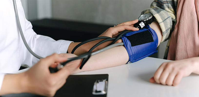 A doctor checking a woman's blood pressure to monitor for preeclampsia.