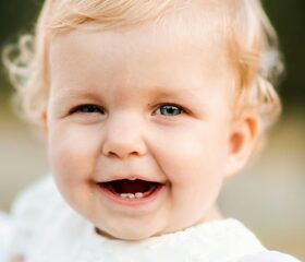 Close-up of a smiling baby boy's face after he's started teething.