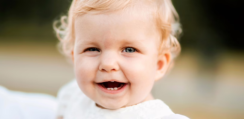 Close-up of a smiling baby boy's face after he's started teething.