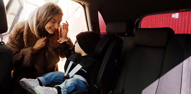 Mother smiling at her baby in his car seat.