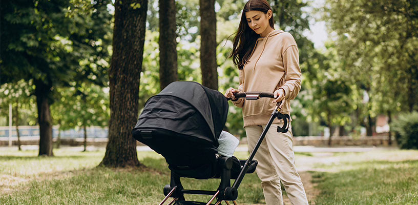 Mom pushing a baby stroller in a park.