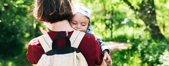 Mother carrying her baby while wearing a backpack-style diaper bag.