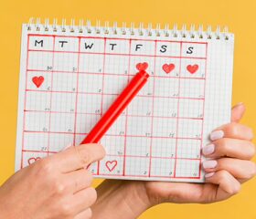 Close view of a woman holding up a period-tracking calendar.