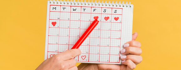 Close view of a woman holding up a period-tracking calendar.