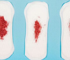 Three pads covered with red glitter representing postpartum bleeding.