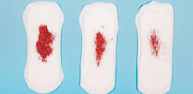 Three pads covered with red glitter representing postpartum bleeding.