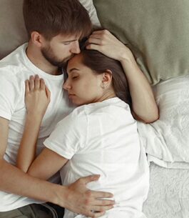Woman who recently had a C-section lying in bed with her partner.