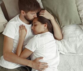 Woman who recently had a C-section lying in bed with her partner.