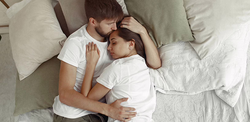 Woman who recently had a C-section lying in bed with her partner.