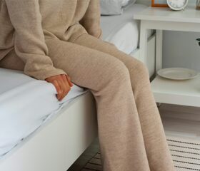 A woman sitting on a bed worrying that she has had a miscarriage.
