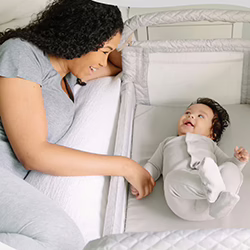Mom smiling at her baby in the Arm's Reach Clear Vue Co Sleeper Bassinet.