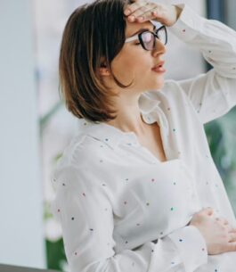 Woman holding her hand to her forehead, feeling forgetful due to pregnancy brain.