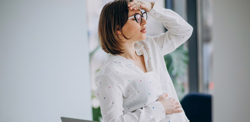 Woman holding her hand to her forehead, feeling forgetful due to pregnancy brain.