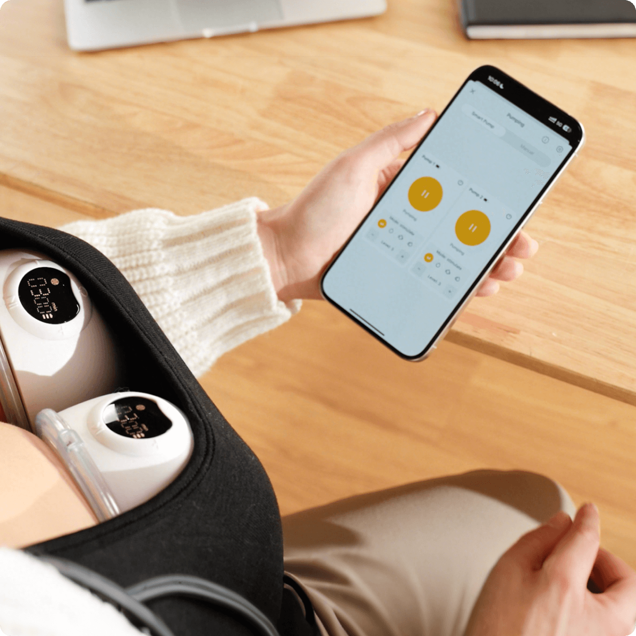 A woman wearing Glow's wearable breast pump and controlling it from an app.