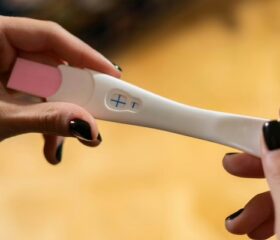 Close view of a woman holding a positive pregnancy test.