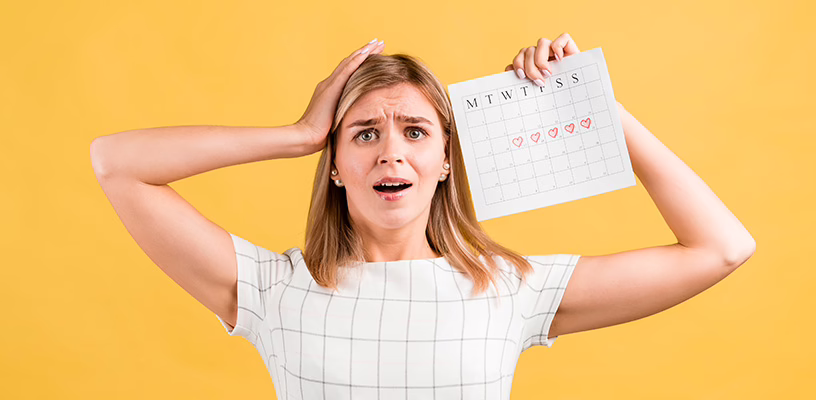 Woman looking confused and holding up a calendar, trying to determine if she's pregnant despite her irregular periods.