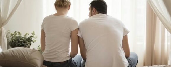 Couple sitting together on the bed during the two-week wait.