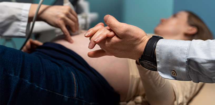 Woman's partner holding her hand as she undergoes an ultrasound check for velamentous cord insertion.