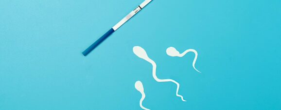 Illustrated sperm swimming towards an ovulation test strip against a blue background.