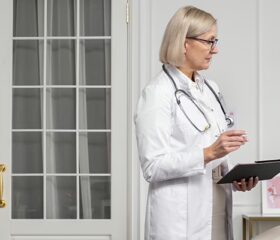 Woman clutching her stomach while speaking to her doctor, as she's noticed the signs of an ectopic pregnancy.