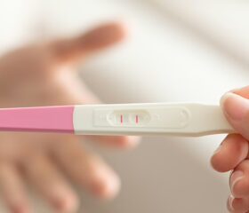 Woman holding ovulation test showing positive result.