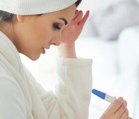Anxious woman staring down at faint positive result on ovulation test.
