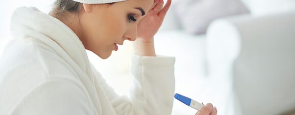 Anxious woman staring down at a faint positive result on ovulation test.