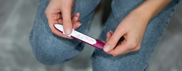 Woman holding a pregnancy test with a false negative result.