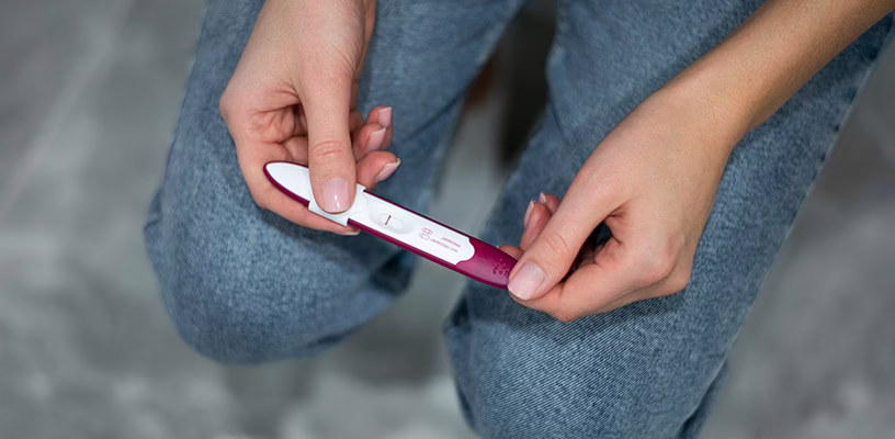 Woman holding a pregnancy test with a false negative result.
