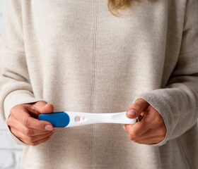 Woman holding a false-positive pregnancy test in her hands.